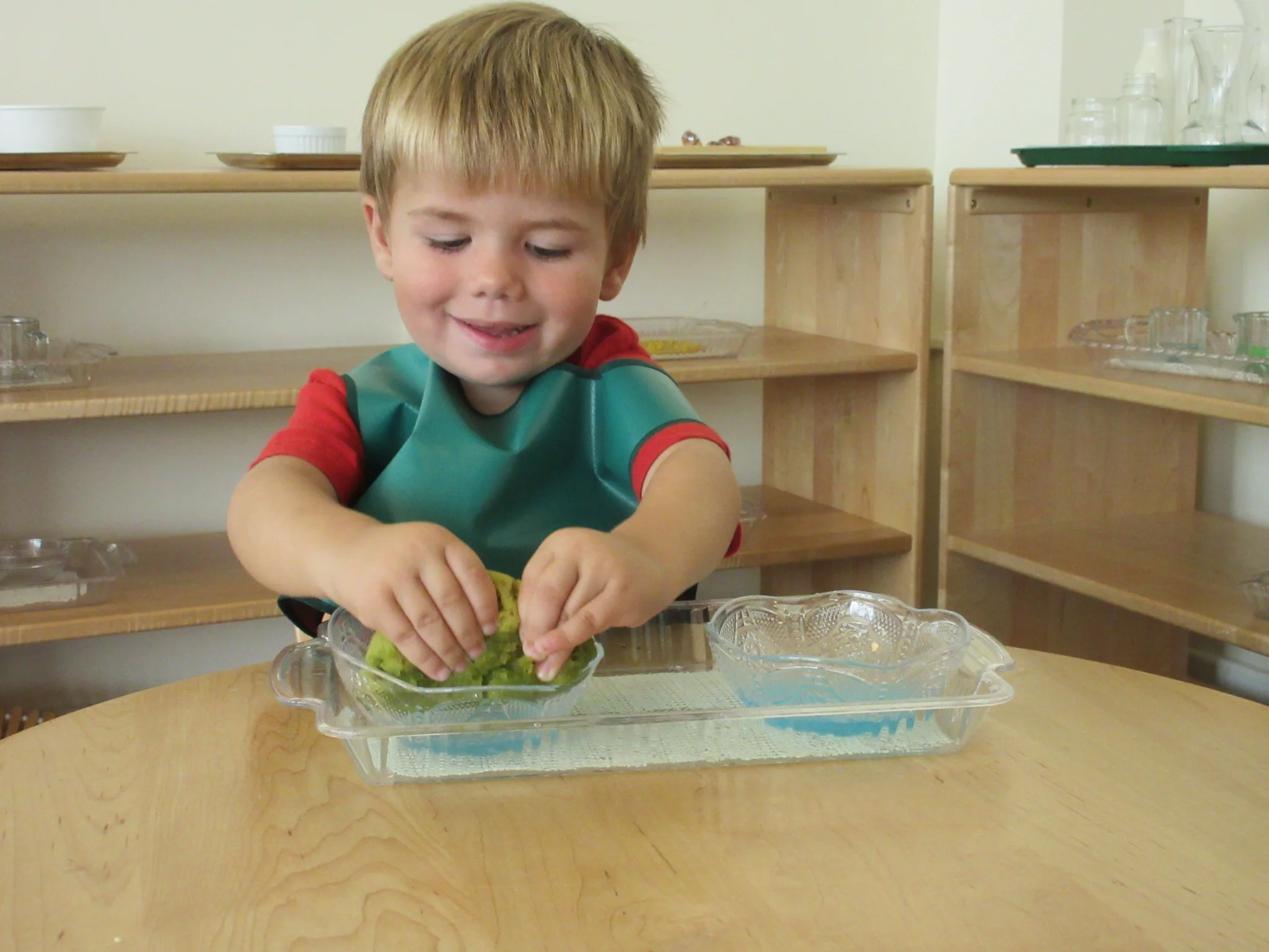 A child explores the joys of transferring liquids with a sponge.