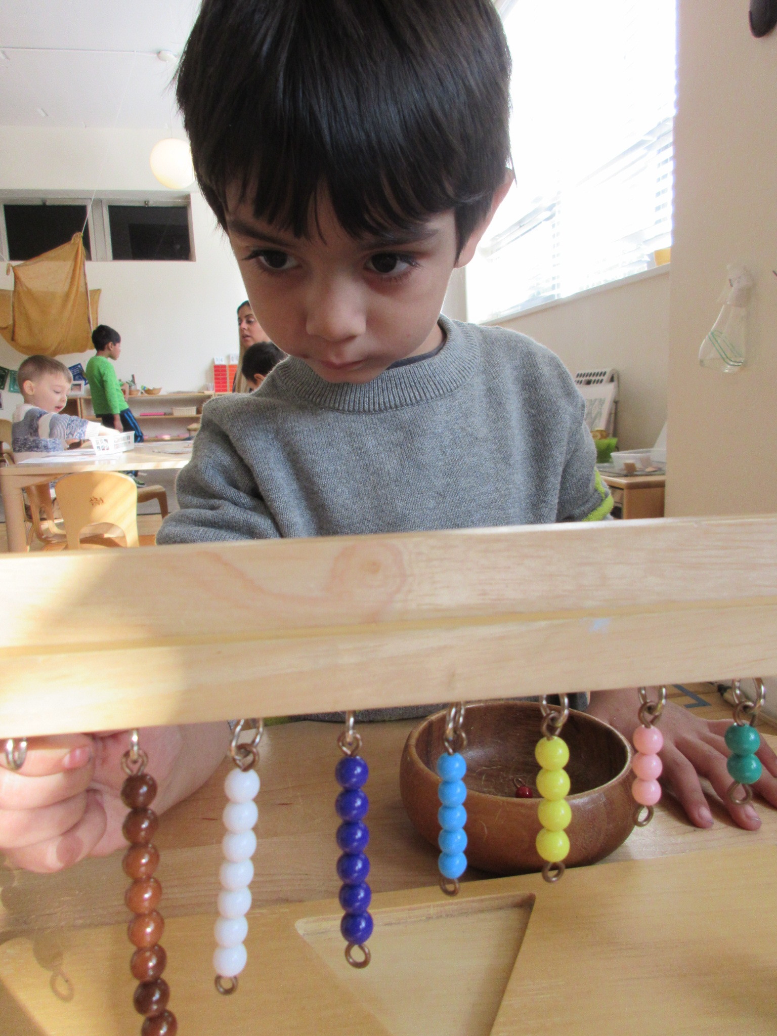 A child explores his numeral-quantity correspondence with the Hanging Beads. 