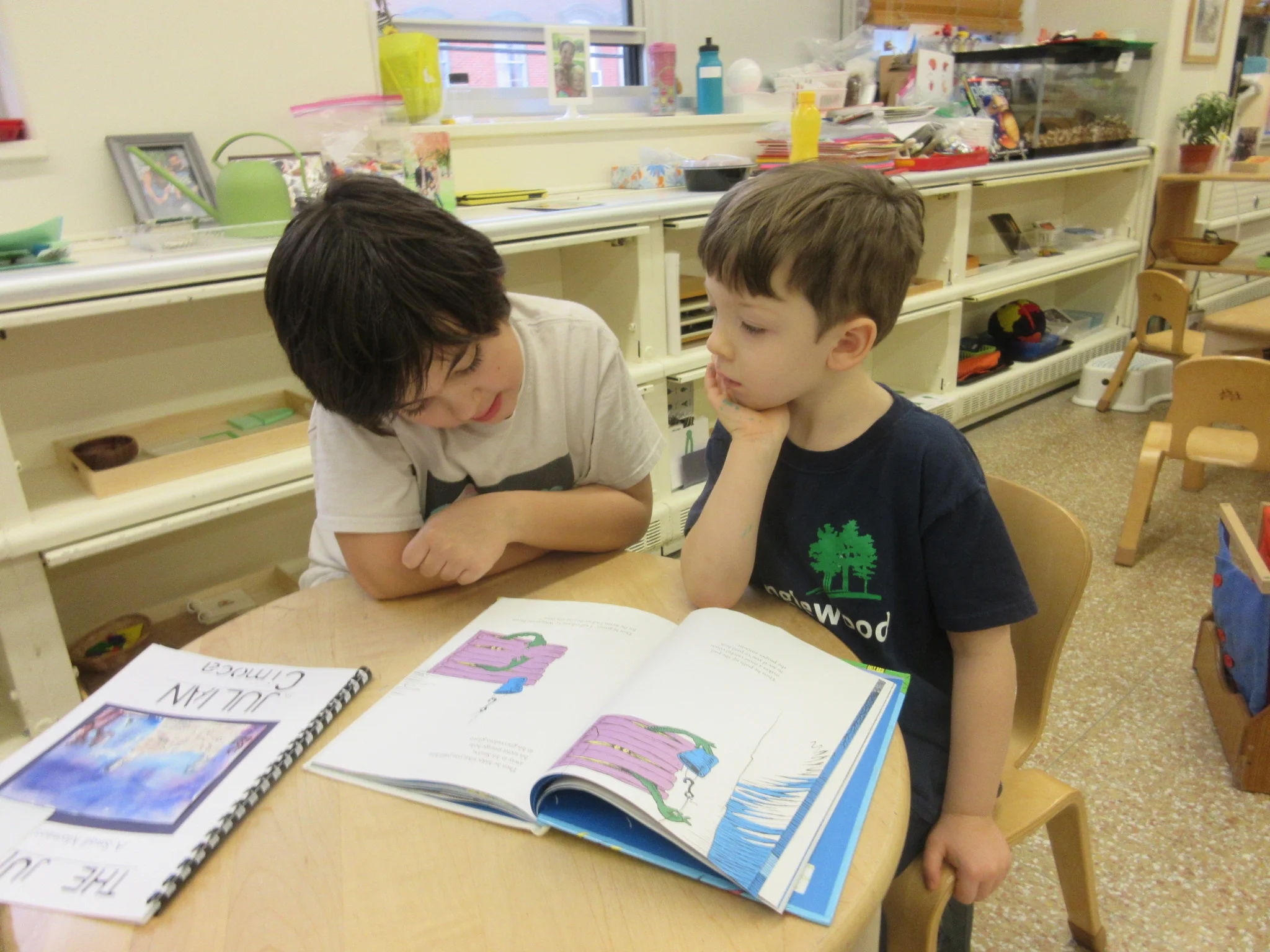 Very focused and keenly listening to the book read by older friend from elementary - reading buddies
