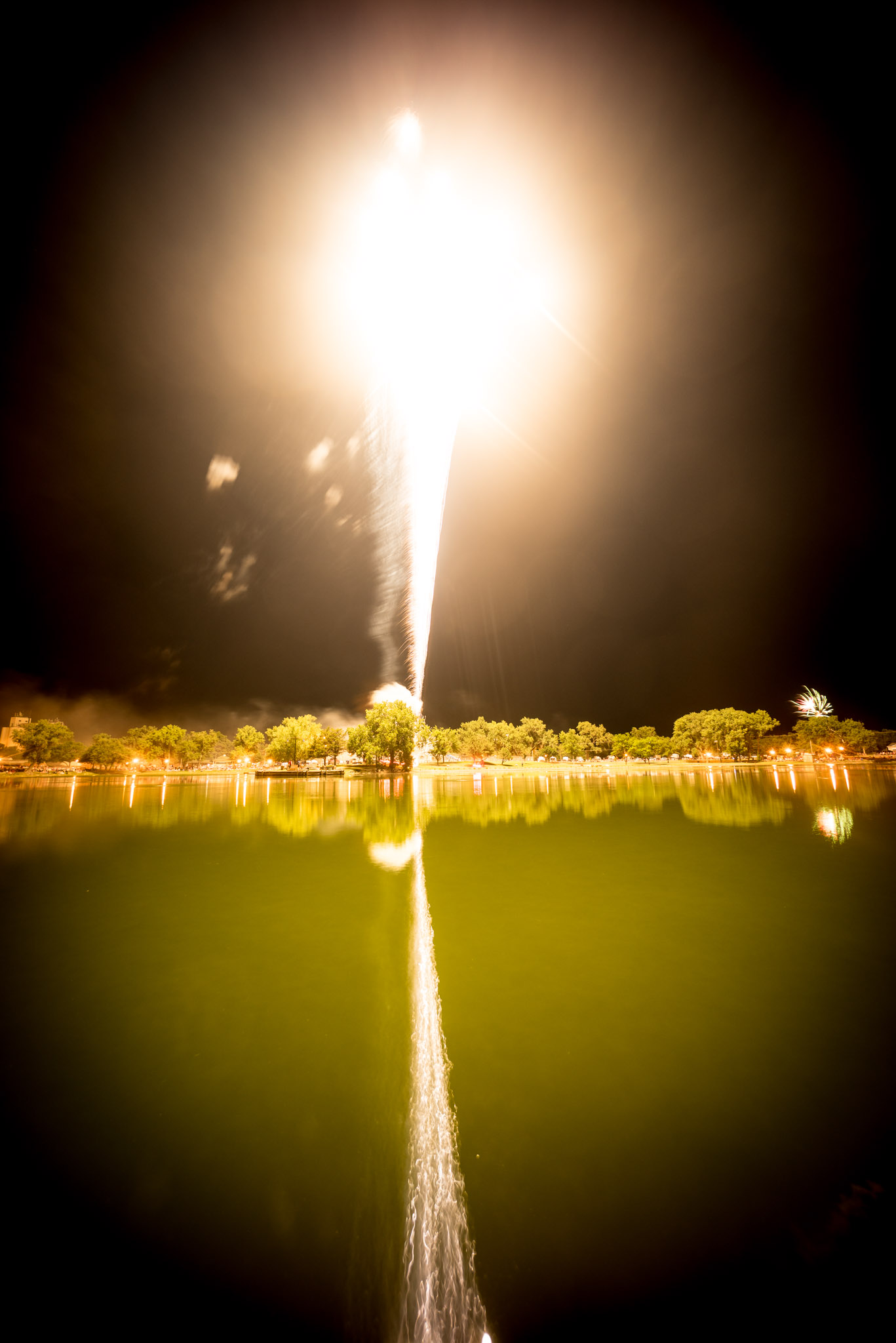 I included this rather ugly, overexposed photo as an illustration that the brightness of fireworks are constantly shifting and you will get a few irredeemably blown out photos. Don't sweat it and overreact to one blown out or underexposed photo. You need to find a happy medium where the greatest number of photos are close to properly exposed, relying on RAW's flexibility to tweak the exposure in post. (Sterling, KS - July 4, 2015.)