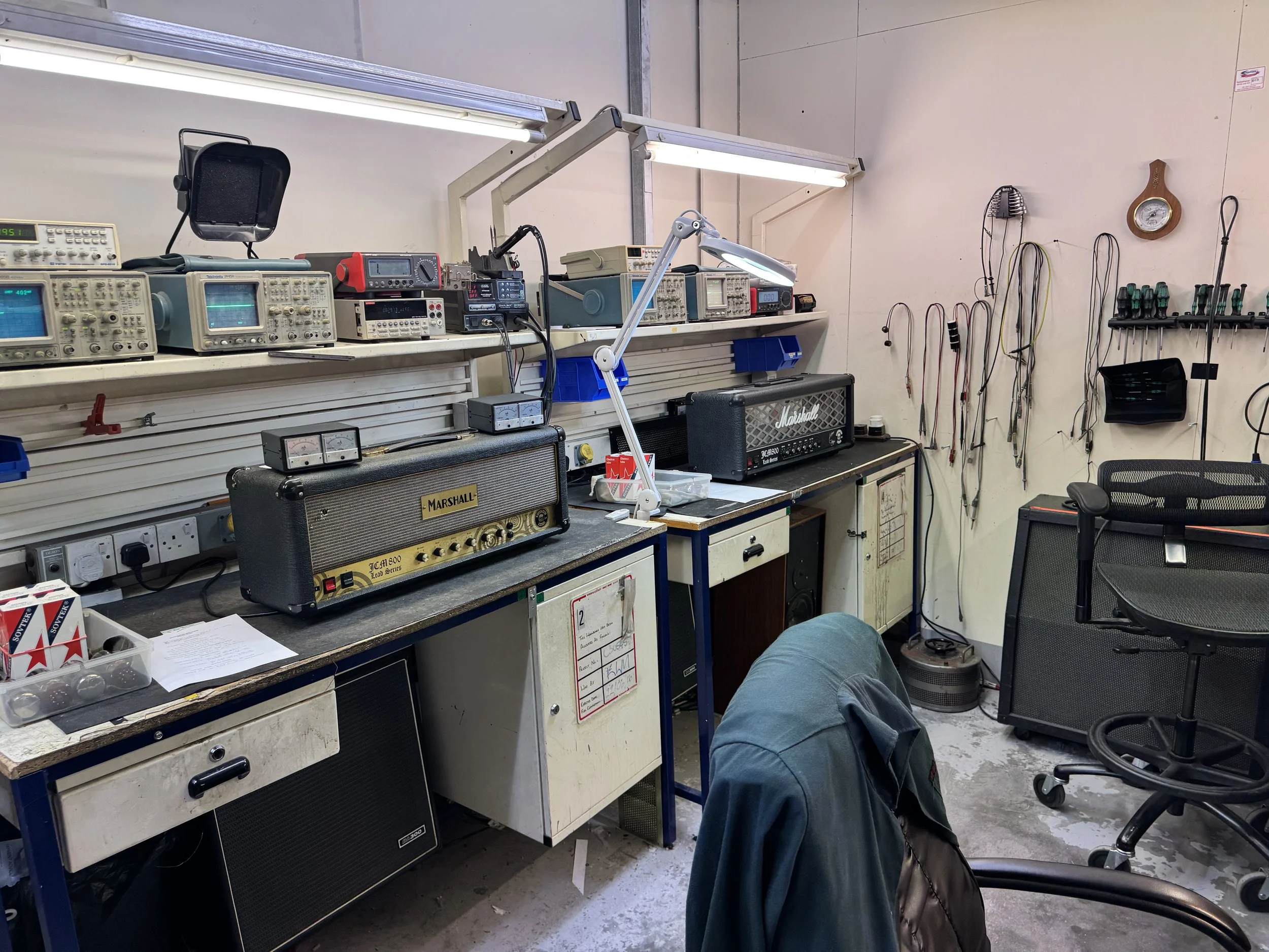 A workshop or electronics lab test equipment, including oscilloscopes and a Marshall guitar amplifiers, arranged on shelves and tables. Bespoke Marshall amplifiers made by Marshall for Zakk Wylde, guitarist  Black Label Society & Ozzy Osbourne