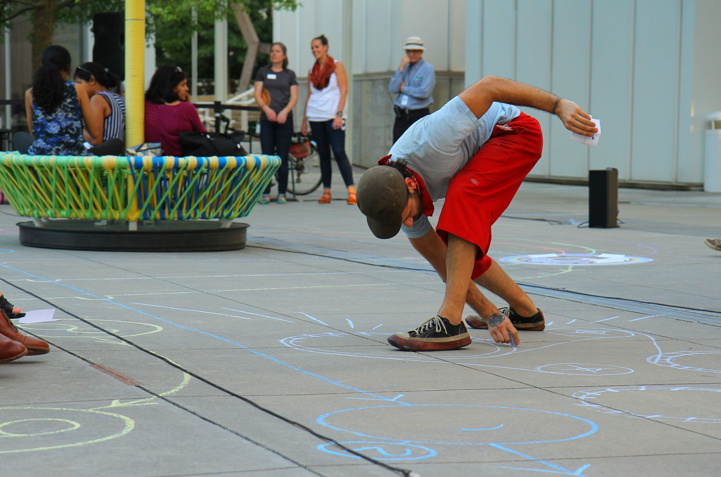 A performer bends over to draw with chalk on the concrete.
