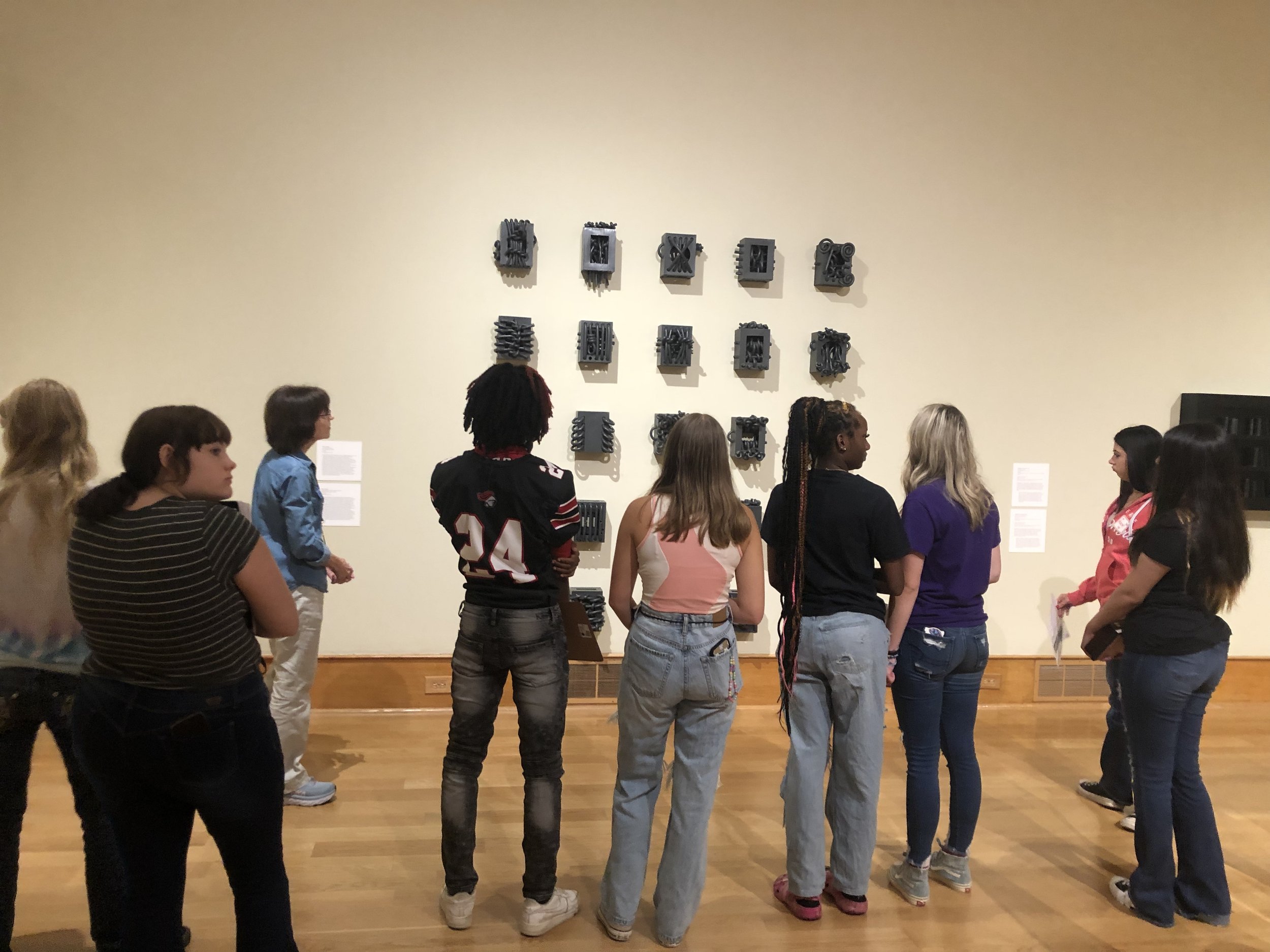 Students look on at Paul S. Brigg's ceramic piece "Cell Personae"