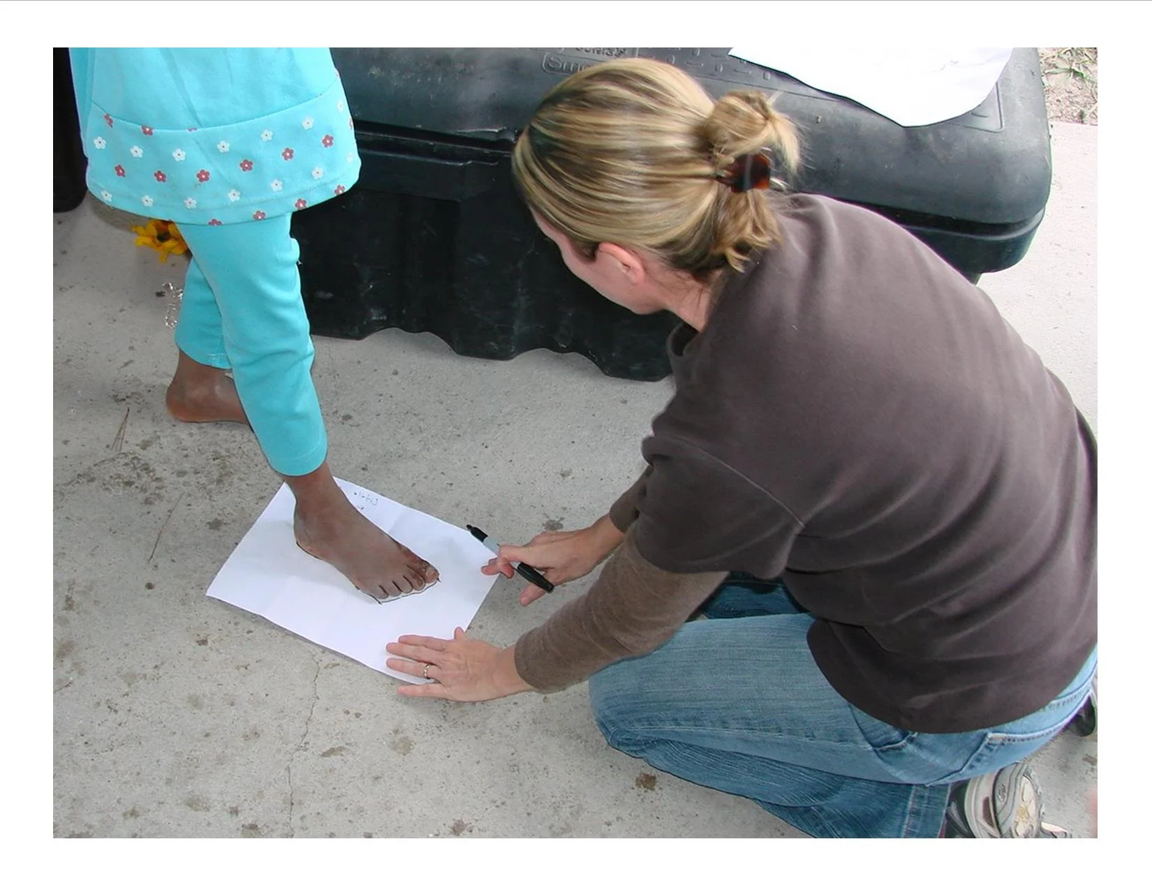 Our founder and missionary, Robyn Breaux, tracing the feet of the children so ER International could buy them shoes