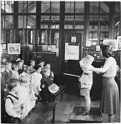 A teacher helps a young pupil conduct an ''orchestra'' during a music lesson at St Joseph's Elementary School, in Upper Norwood, England., in 1943. The boy is using drumsticks or xylophone beaters to conduct the rest of the class, who are playing tambourines, triangles and cymbals .