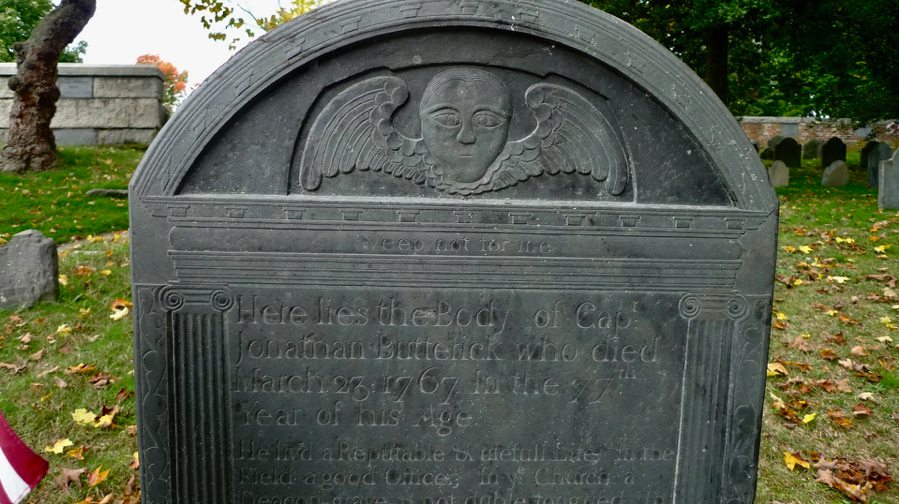 Old Hill contains some classic and noted examples of New England stone carving: seraphim, death’s heads and hourglasses that have run out of time. This is the resting place of Captain Jonathan Butterick (1690-1767). The grave says “Weep not for me’’.