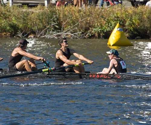 A coxswain (far right), sitting in the stern , facing the rowers, at the Head of the Charles Regatta , an annual event.