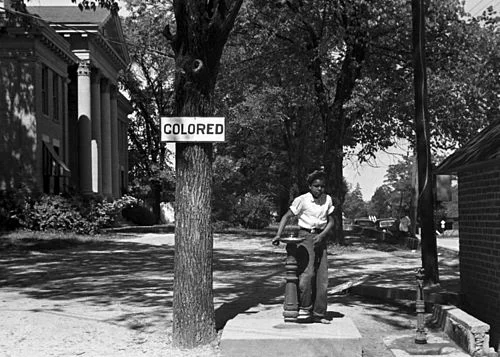An African-American child at a segregated drinking fountain on a courthouse lawn in North Carolina , in 1938.