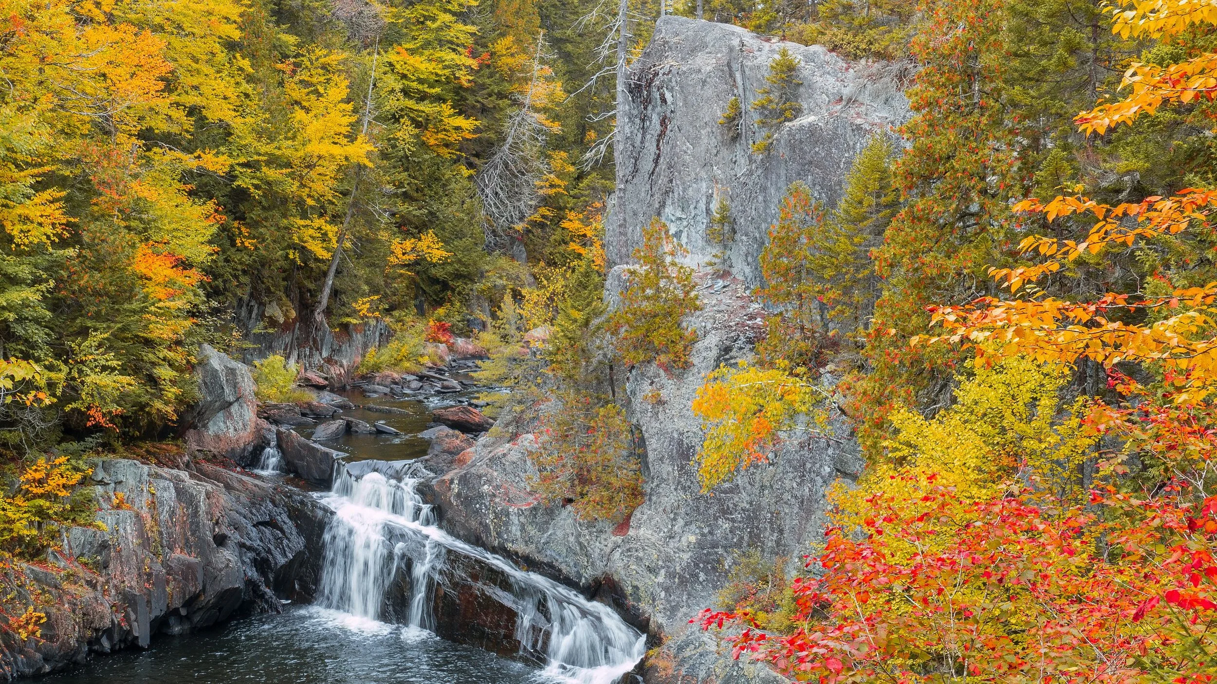 Cheery fall foliage brightens the cliffs of Buttermilk Falls in Gulf Hagas, Maine. Gulf Hagas is sometimes called “The Grand Canyon of Maine’’.— Photo by Andythrasher&nbsp;
