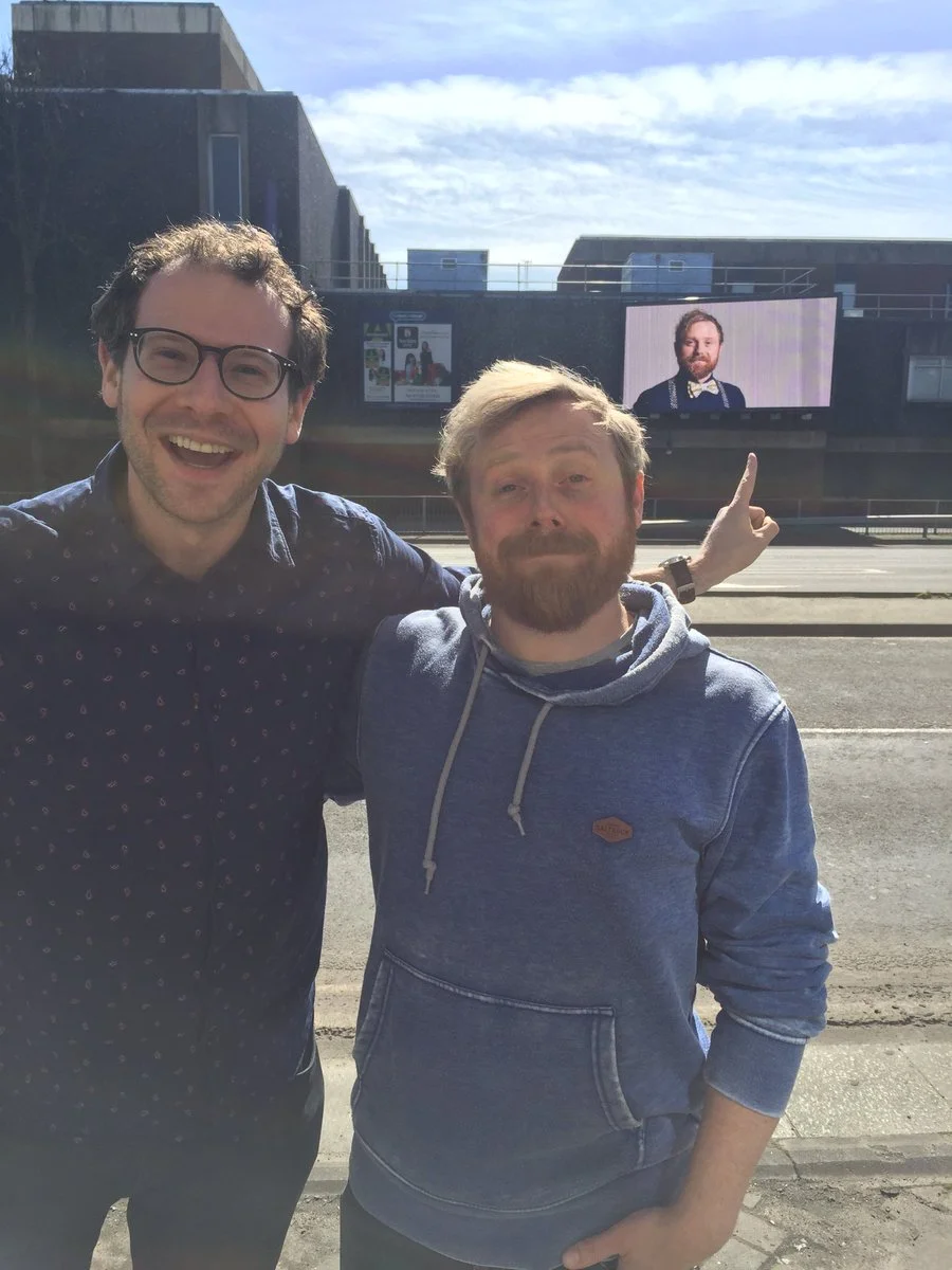 Olly and Ollie bear witness to a mid-sized billboard of Ollie's face. In Slough.