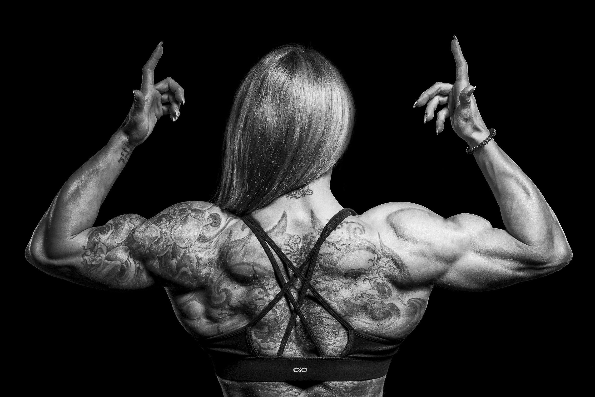 Female bodybuilder flexes her back. 