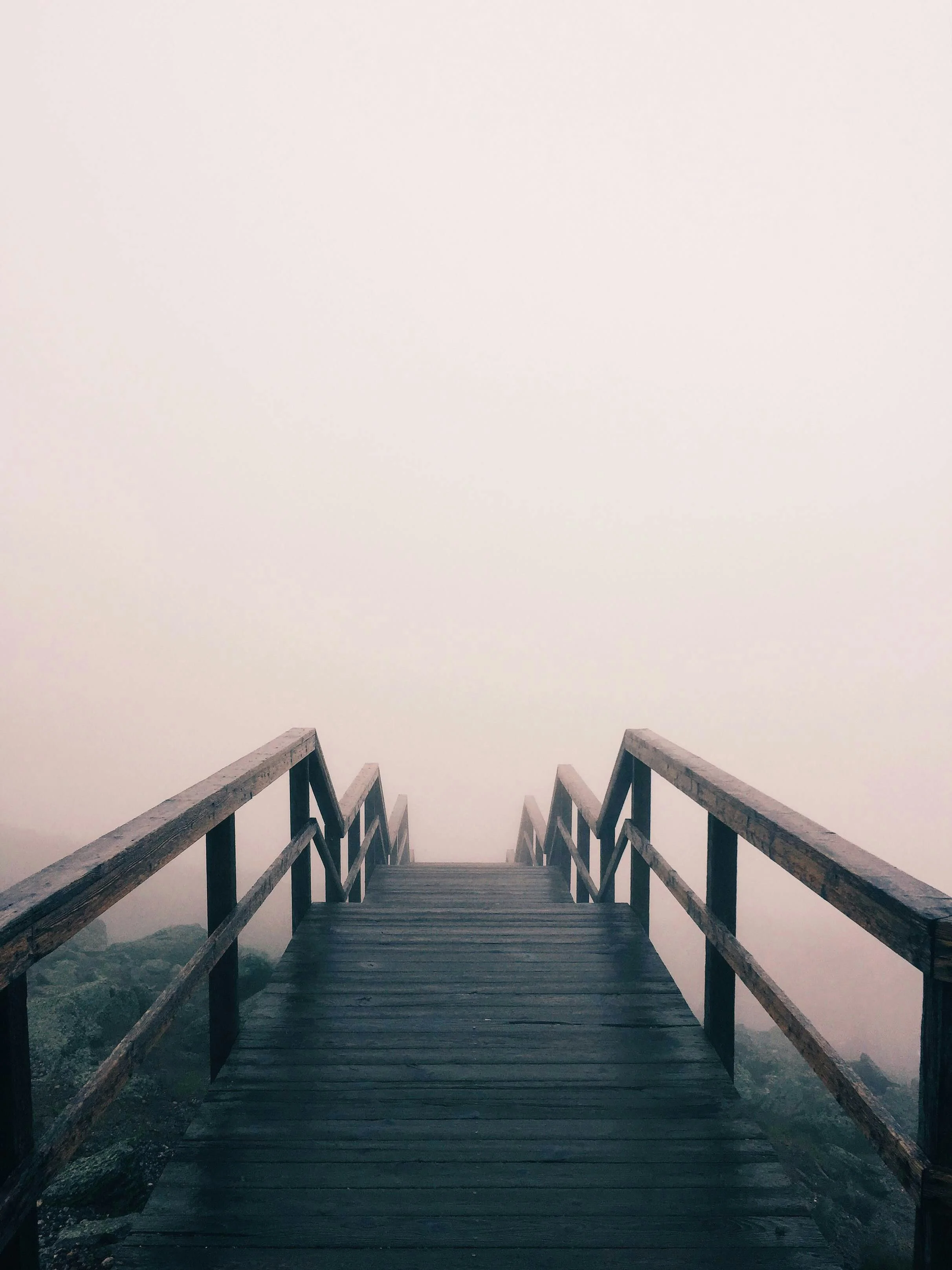Wooden boardwalk disappearing into thick fog, symbolising the uncertainty parents feel about their children's future.