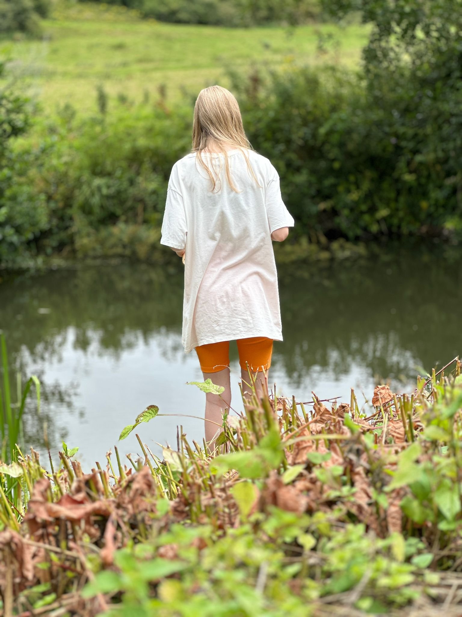 Girl facing back looking into a river.