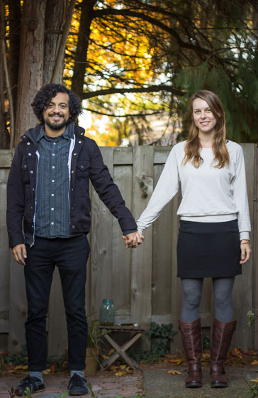  Couple standing in hipster pose outside smiling and looking at the camera. 