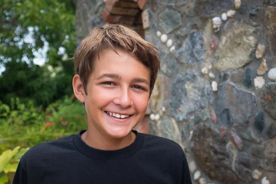 Close up of child outside smiling at photographer.
