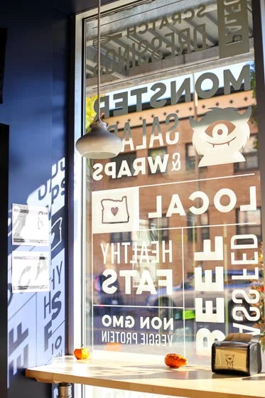 Tall front window covered in white decals with sun casting shadows on the wall