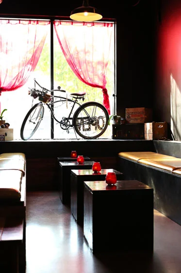 Cozy seating in restaurant with benches and a bike in the window backlit from sun