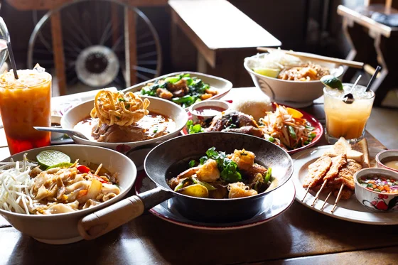 Backlit table full of Thai food and beverages