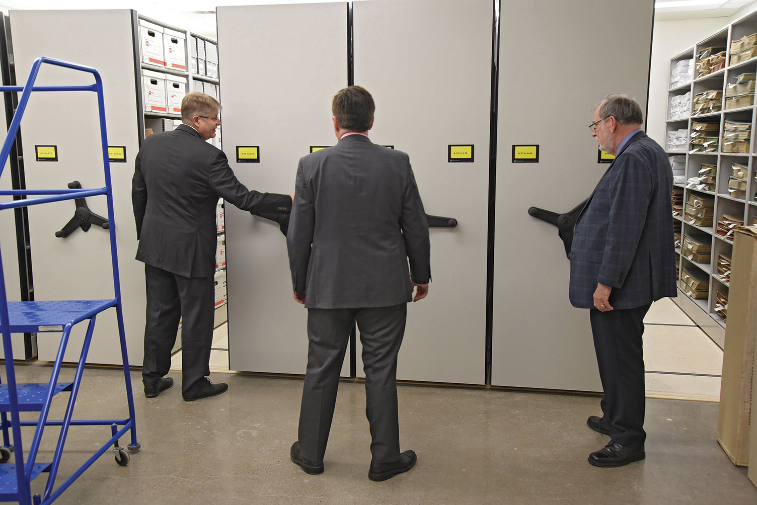 The new archives, on the second floor of the library building at 254 Pinnacle Street, provides 5,000 square feet of storage and work space meeting modern archival standards. Mark Fluhrer, Neil Ellis and Orland French sample the state-of-the-art rolling doors that provide access to materials. Photo by Bob House / courtesy Community Archives of Belleville and Hastings County