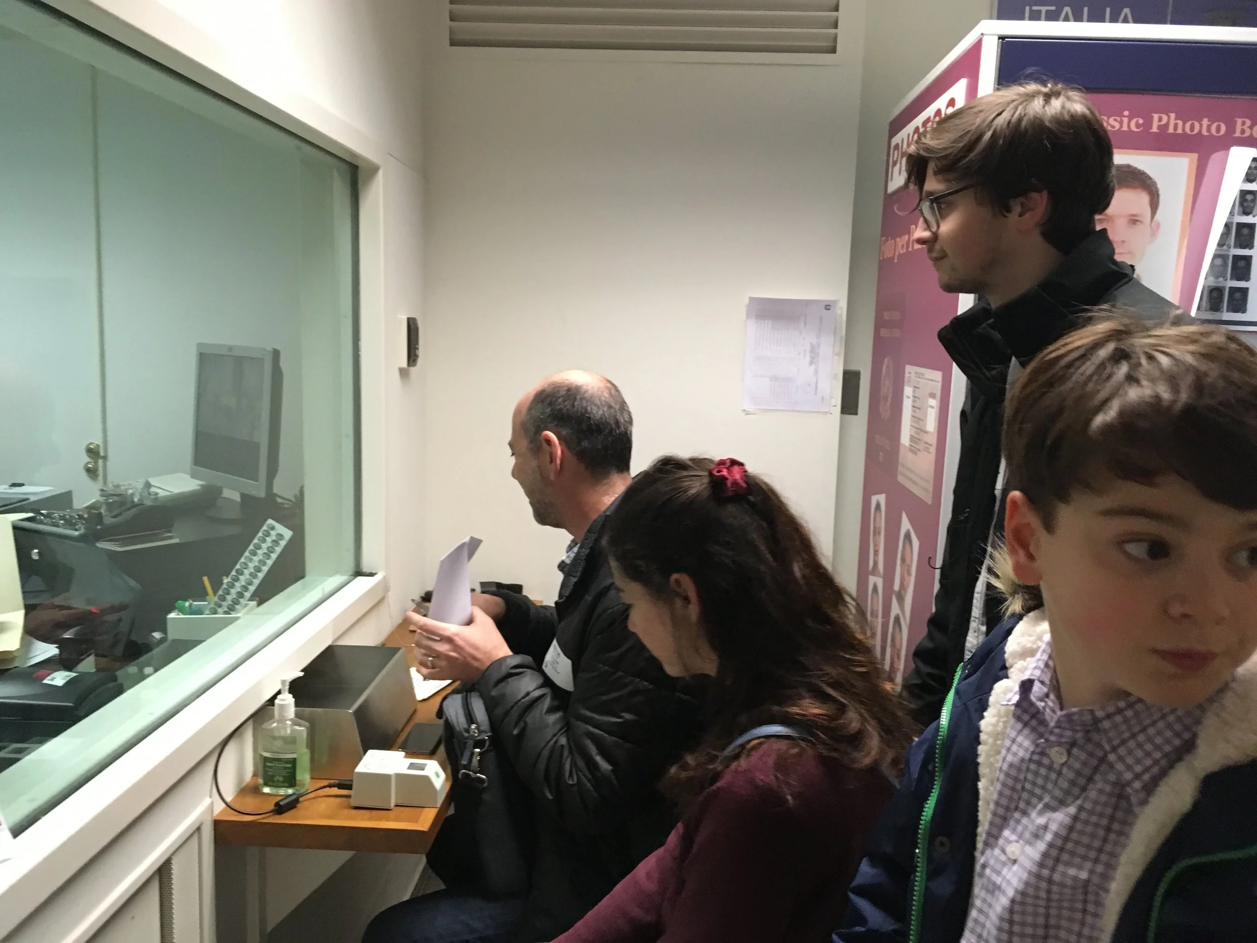 Our visit last week, with the plexiglass and the little drawer to shuttle documents back and forth. Unlike last time, this time there was much shuttling.