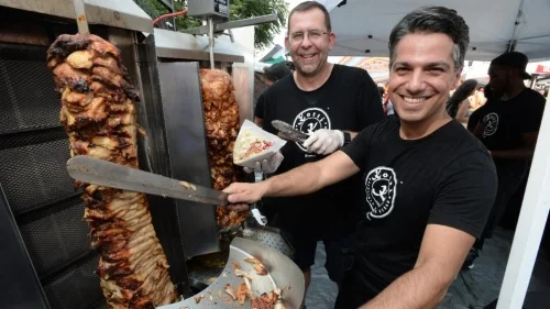 © TOBIAS EVERKE Erkan Emre slices chicken from the rotating grill-spit, while partner Michael Stark fills pita bread with chicken, vegetables and greens. 