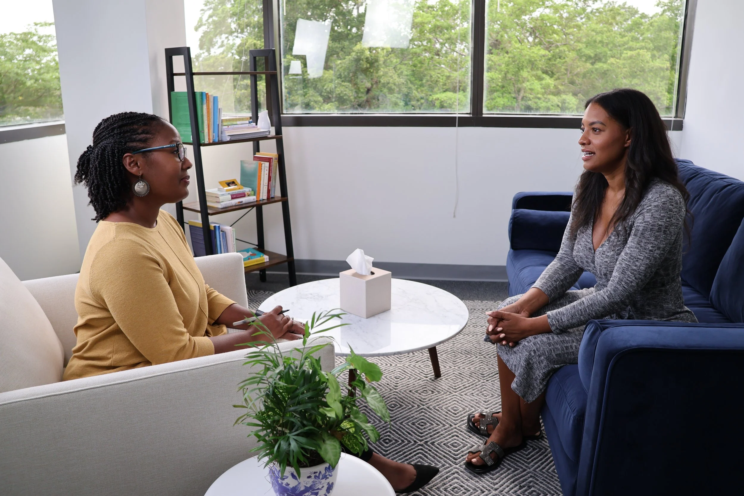 A Black female therapist listens to her client, a Black woman, and uses CBT to discuss learning to rest as part of healing.