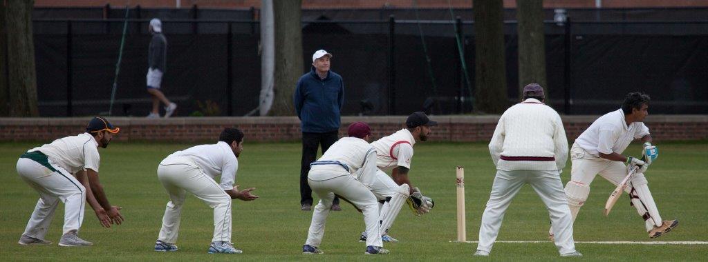 Fielders crouch, with hands extended, in fielding positions behind the batsman as he prepares to face a delivery. (Photo courtesy of the C. C. Morris Cricket Library Association.)