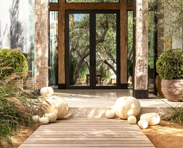 The art of simplicity says a whole lot! Notice the interaction of very green plants and earth toned planters, both in round, textured shapes to emphasize the roundness of earth, and therefore, the integrity and beauty of the organic. Here, a play on browns and greens of fall and - yup you guessed it - off-white pumpkins remind you Fall can be warm and stylish. Did you notice the mirror doors reflecting the bare trees? So Fall! Mimic this look by picking up random branches outside - yes outside - of similar heights and stick them in your green plants, to look similar to the back of a porcupine.