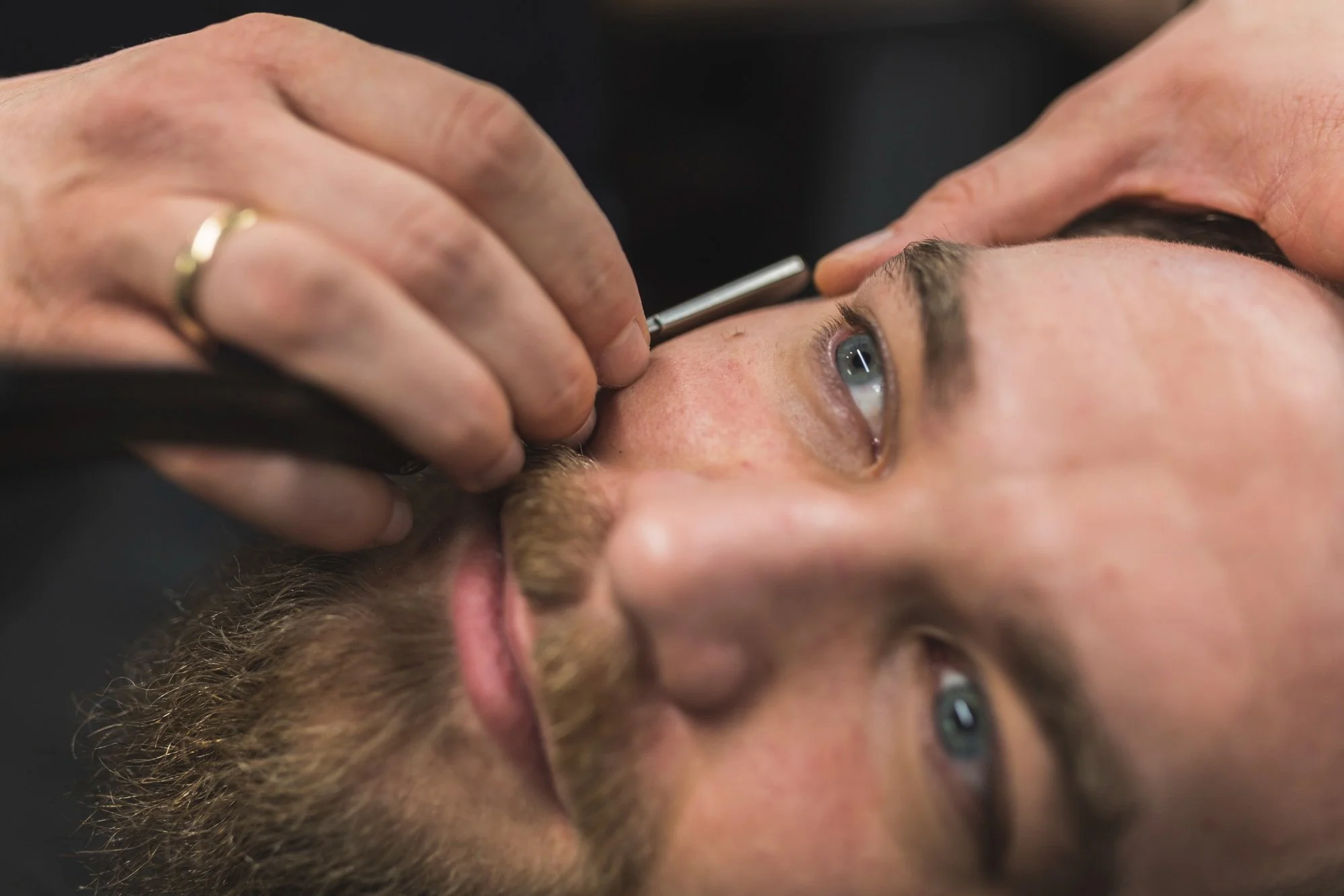 Straight razor shaping a man's brow line during a men's eyebrow grooming appointment.