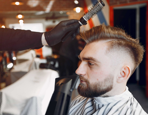 Experienced barber shaping hair and beard with precision clippers in a classic barber shop near Roscoe Village.