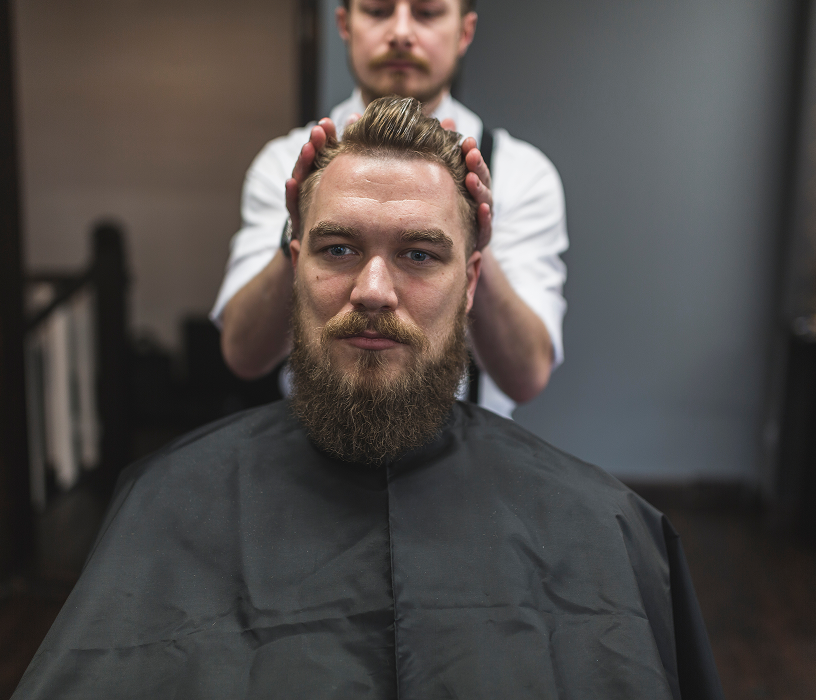 Man in sunlight with short curly perm and beard showing voluminous types of perms for men with texture.