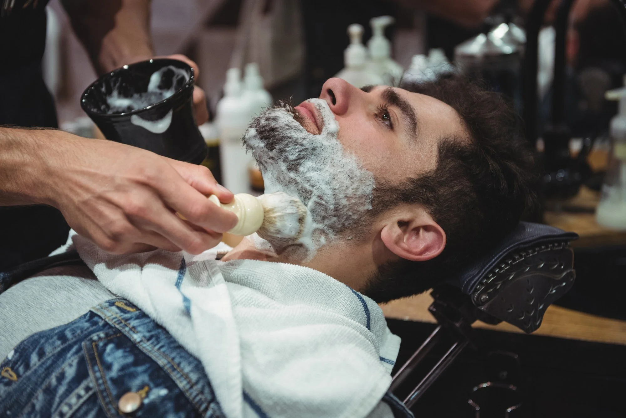 Warm shaving cream applied to a client's beard with a brush before a beard trim service.