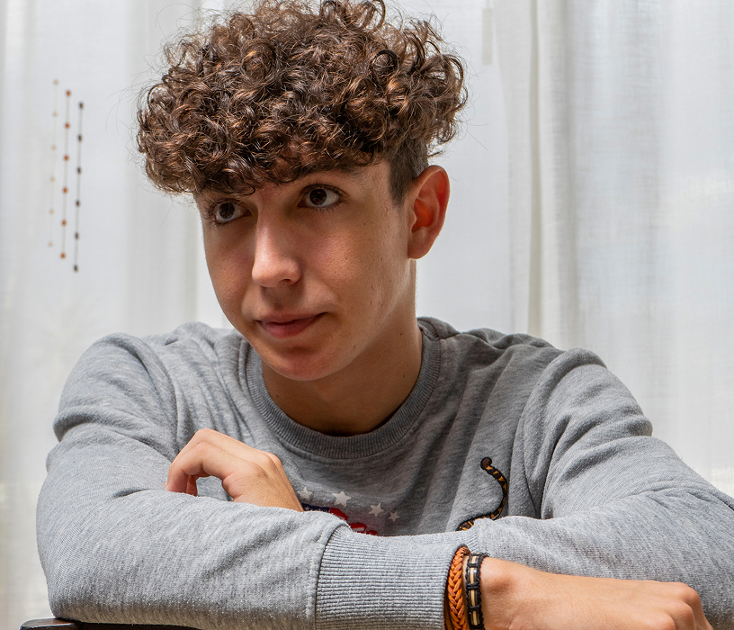 Man outdoors with medium-length tousled beach wave perm showing one of the most natural-looking men's perm styles.