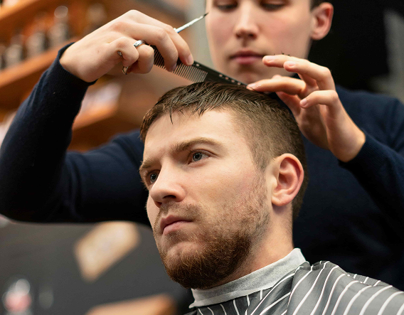 Experienced barber trimming a full beard and haircut for a male client in a Buena Park grooming studio