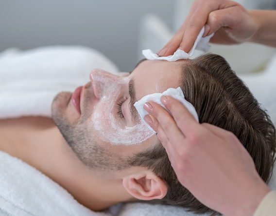 Man gently applying exfoliating solution at home, highlighting visible glycolic peel benefits for smoother skin.