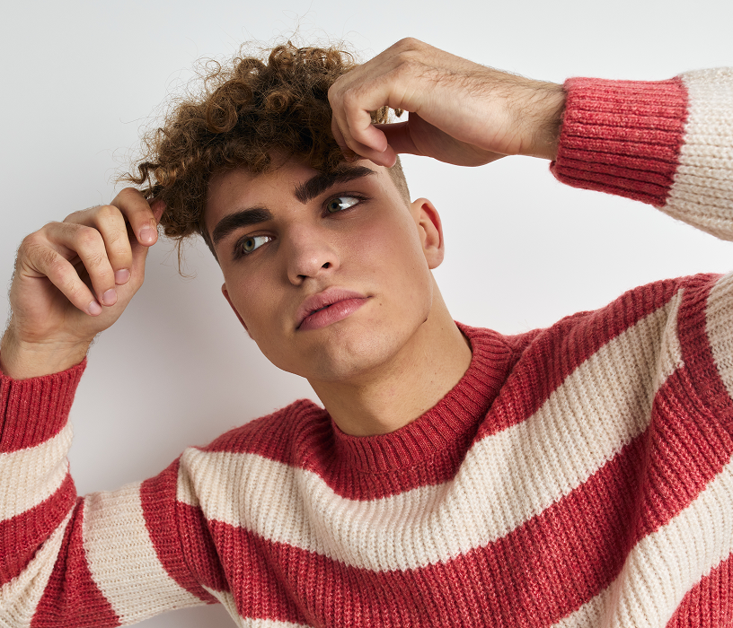 Stylist shaping a man's loose wavy perm at a salon, showing the finishing stage of men's perms for short hair.