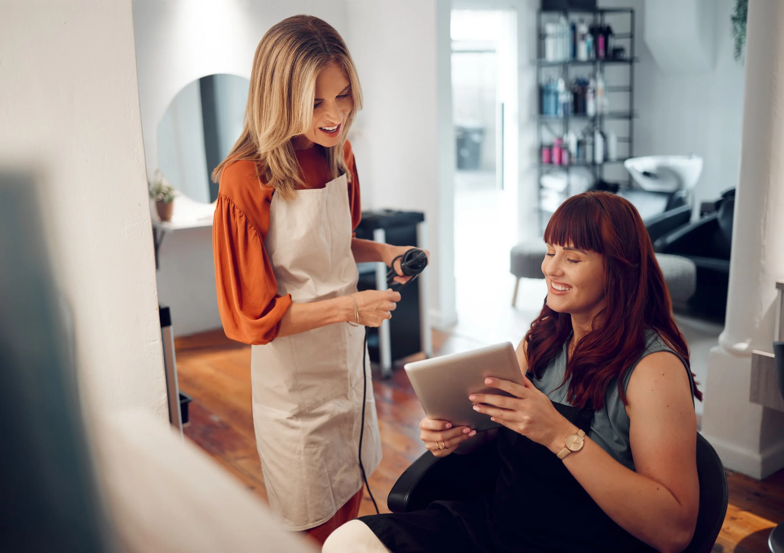 A stylist and client looking at a tablet, an example of what to expect at your first salon visit.