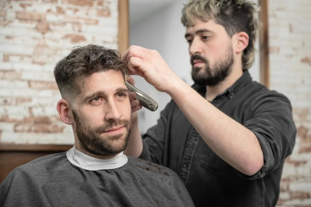 Barber trimming a client’s hair during a consultation-focused men’s haircut, illustrating how much a haircut should cost based on skill and service.
