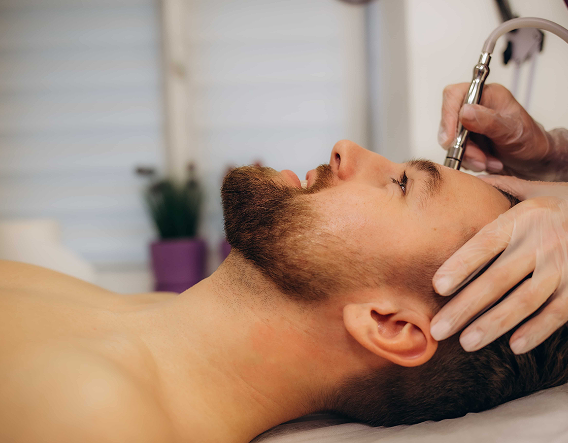 A male client is undergoing diamond-tip microdermabrasion treatment for deep skin resurfacing in a Chicago clinic.
