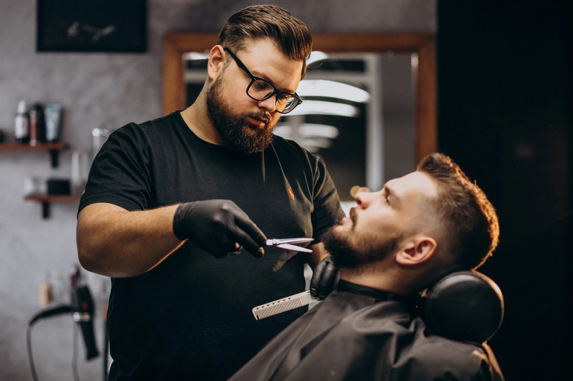 Stylist trimming a client's beard with scissors and a comb during a beard trim service.