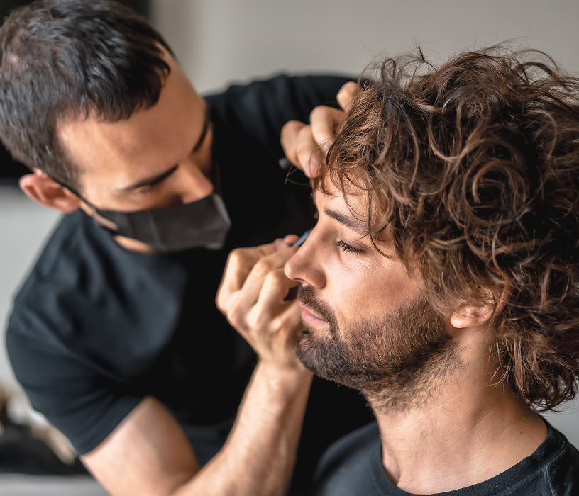 Stylist applying perm solution to a client at a men's perm salon Chicago in a professional grooming environment.