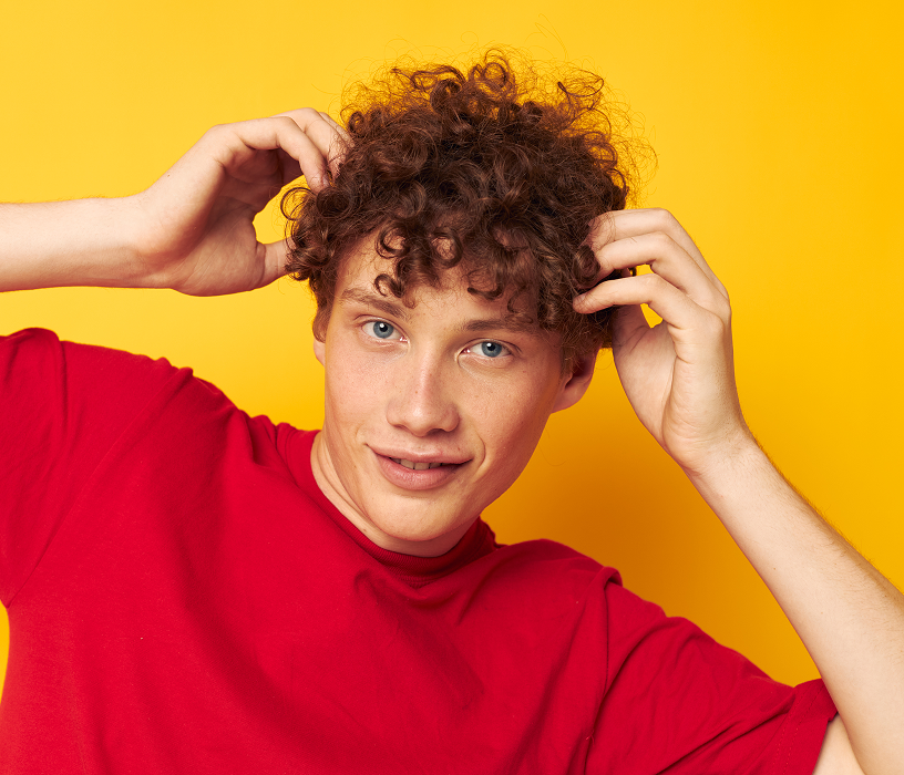 Man with voluminous curly perm styled upward showing what men's perms for short hair look like on medium length hair.