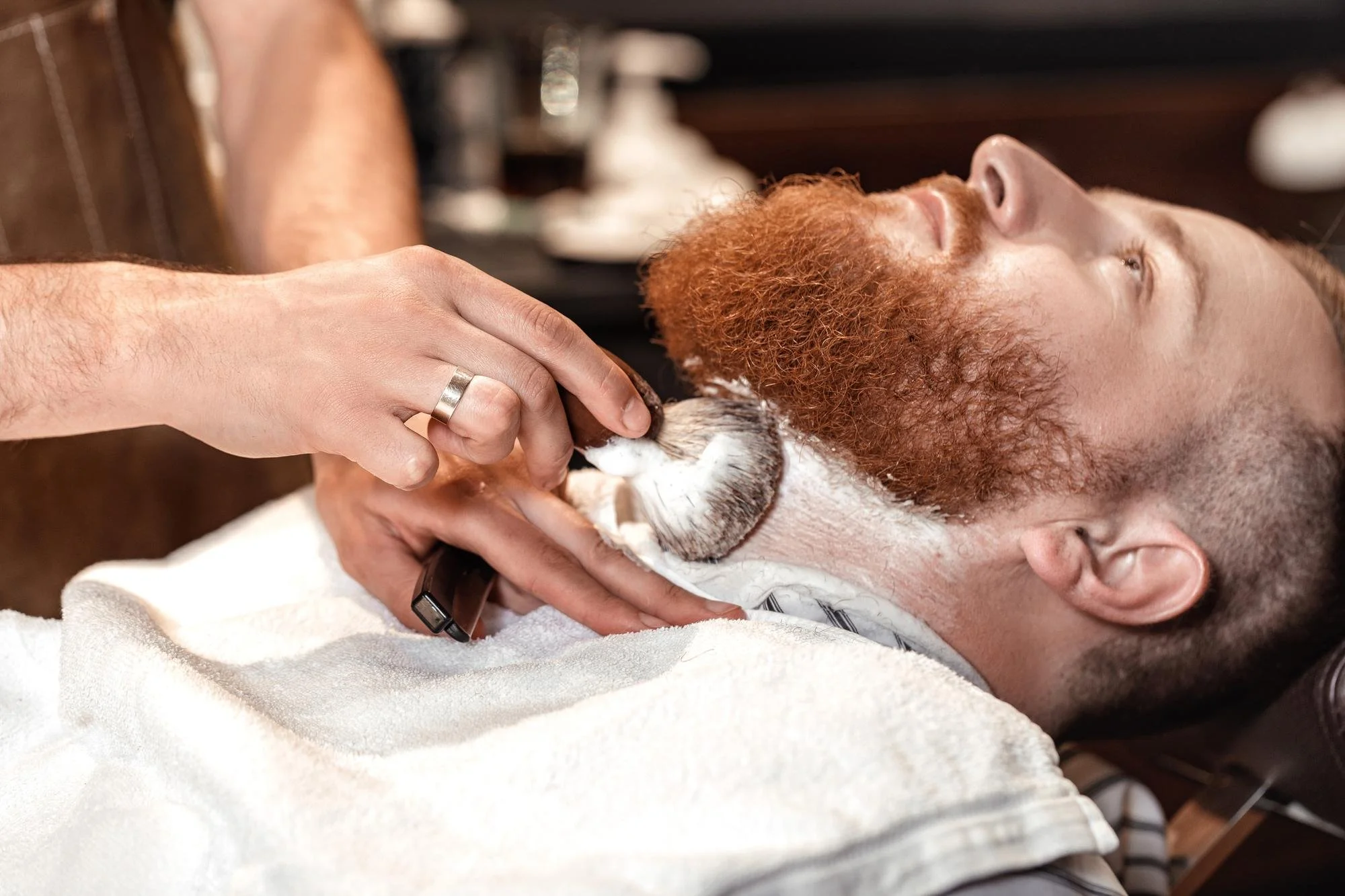 Barber shaping a red beard with a razor, demonstrating male self-care and evening men's self-care routine.