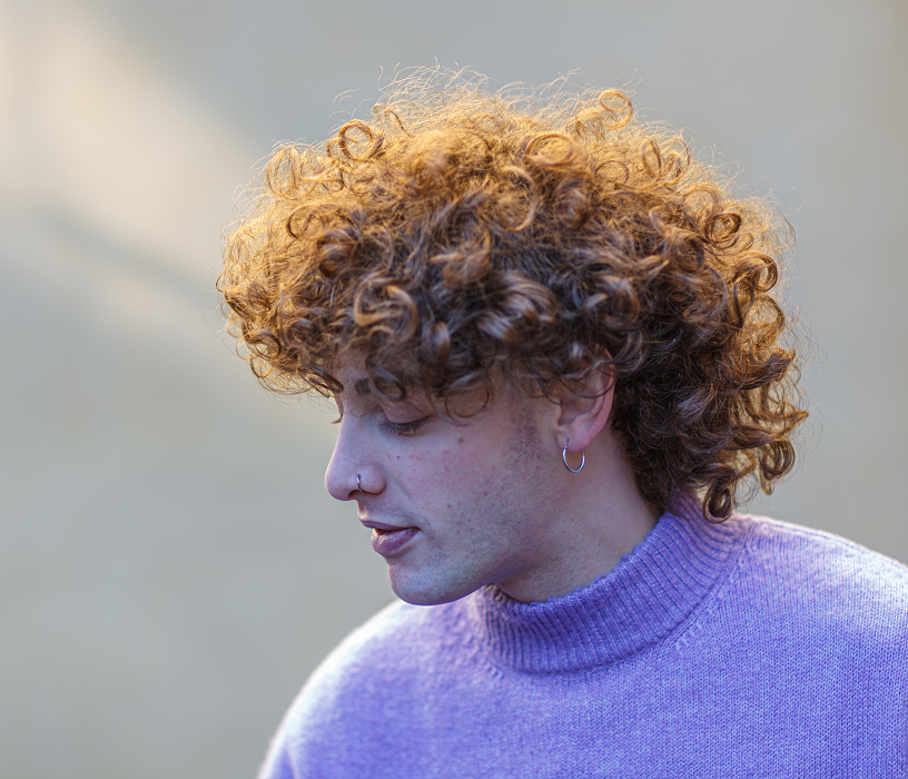 Stylist working on a client's hair at a salon appointment, showing what a men's perm cost covers in a professional service.