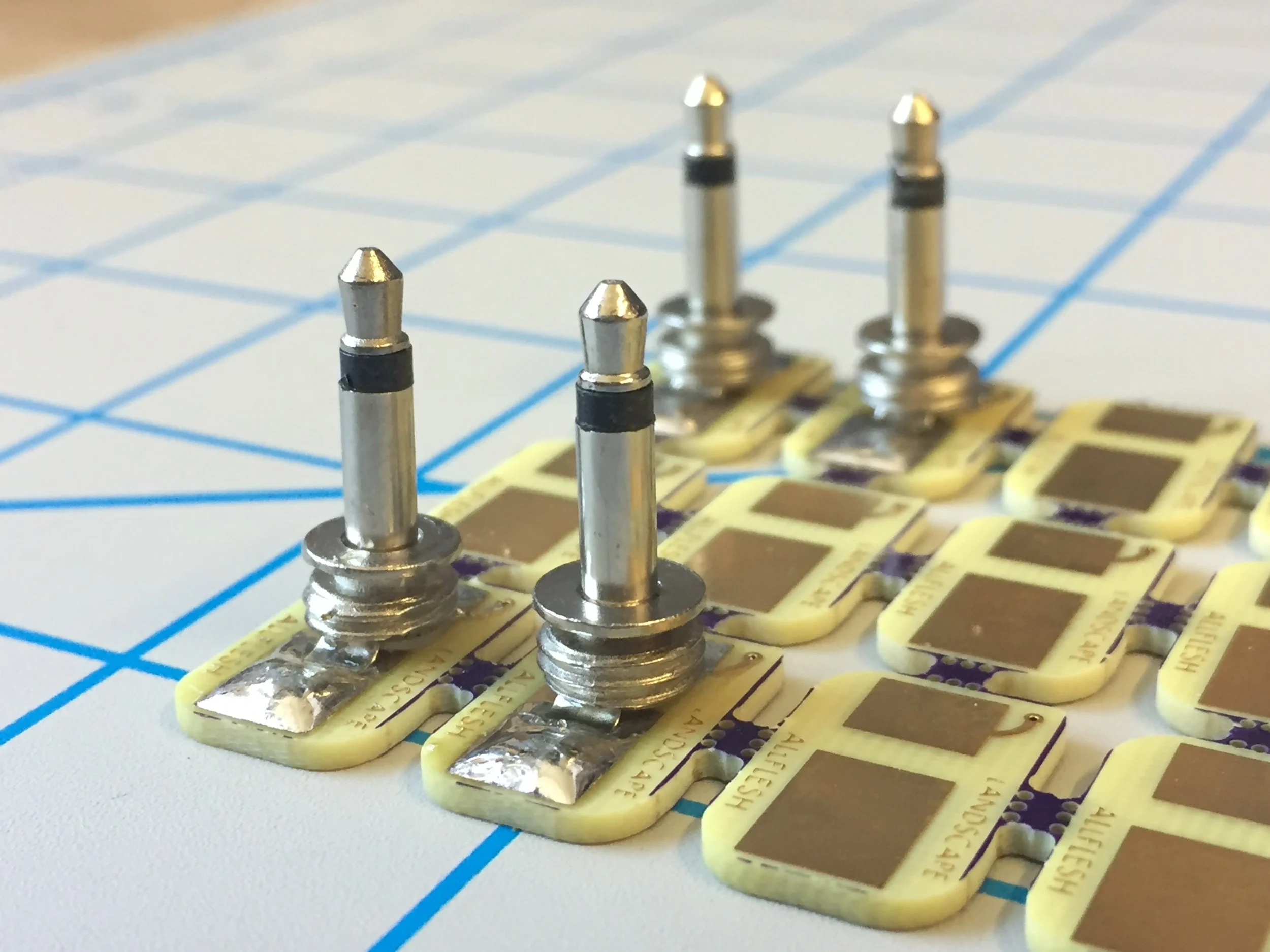 7.  After everything is all happy and aligned move to soldering the larger lugs but  take   caution  as the plug's body and tip will get very hot during soldering. Take care to make sure all edges are covered with solder. After they have sat for about two minutes they will be cool enough to handle. If you didn't break apart the pcbs before soldering (I know my images are misleading) use clippers on the perforations between boards and make sure to not apply pressure to the plugs themselves.