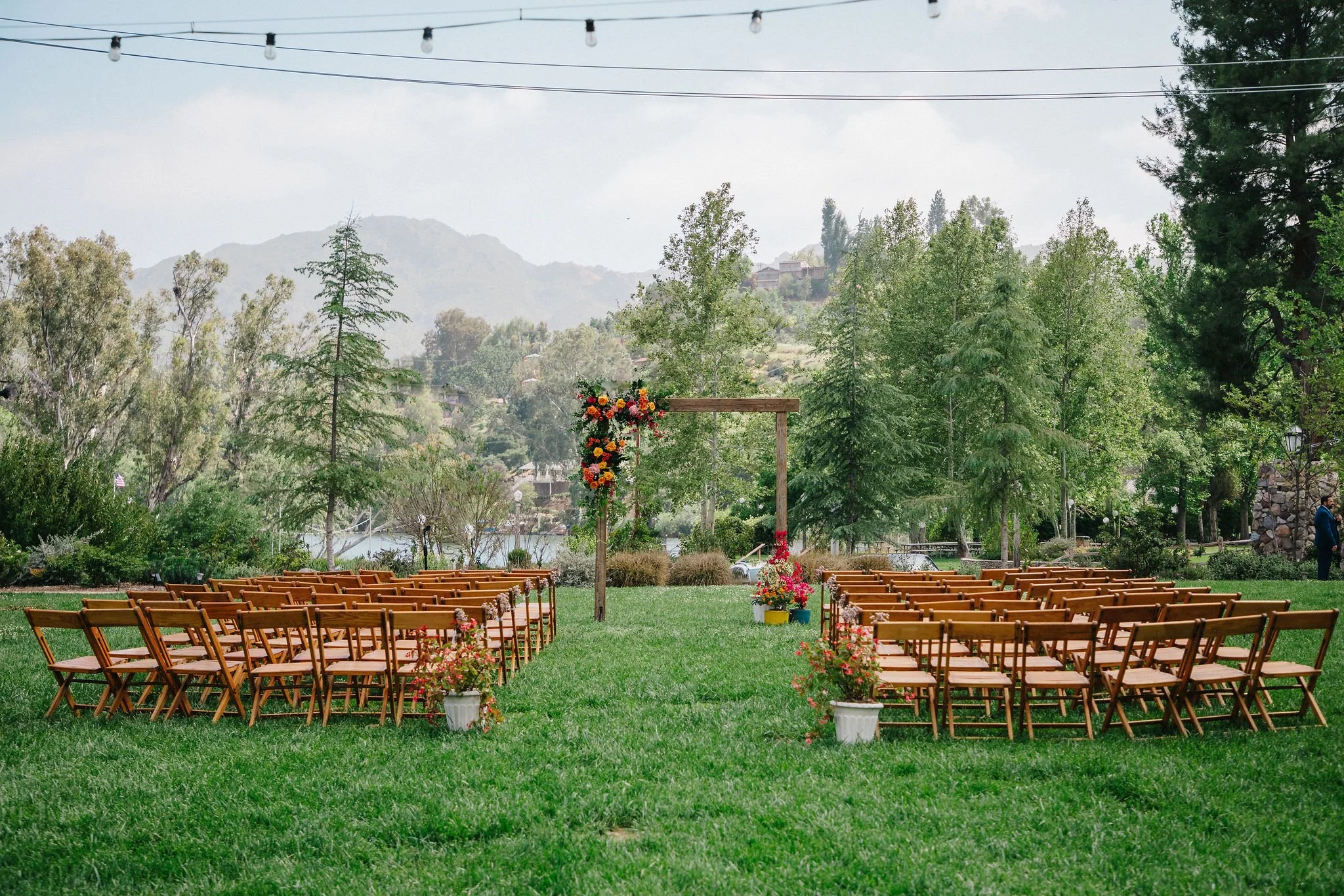 Ceremony is set for an April wedding on a lush green lawn surrounded by trees and mountains at The Lodge at Malibou Lake in Los Angeles CA.