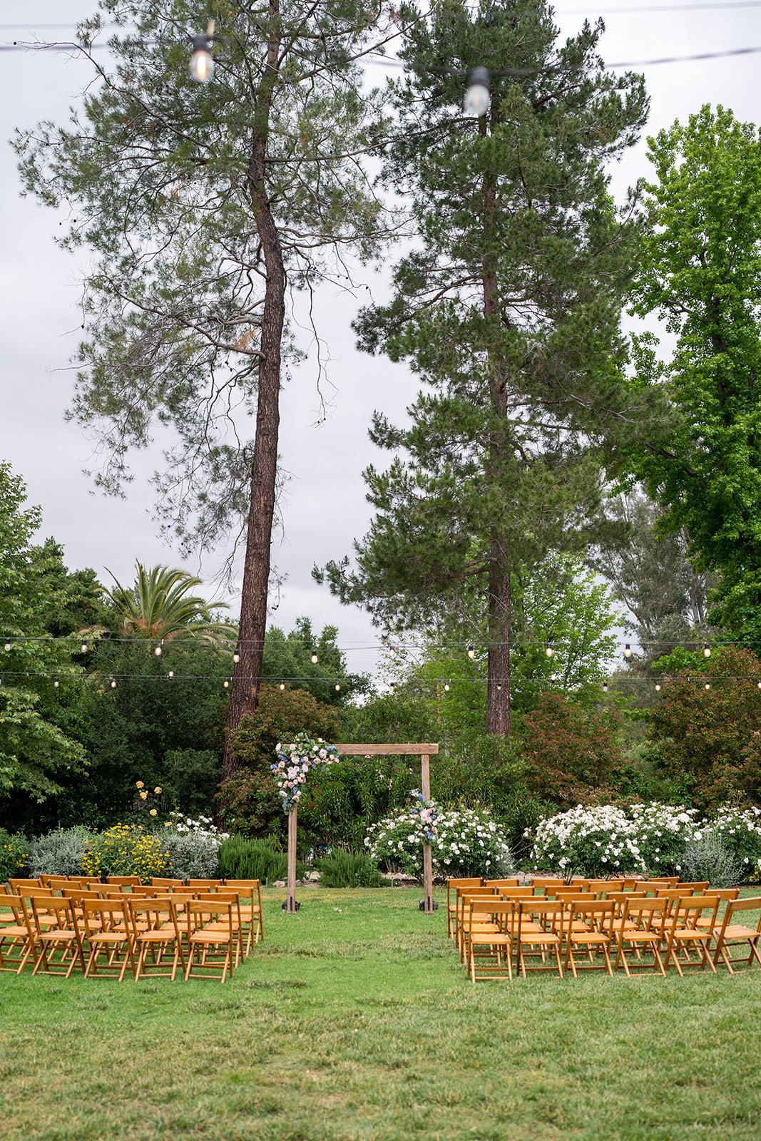 Vintage wood folding chairs are lined up for a wedding ceremony outdoors on teh lawn in May at The Lodge at Malibou Lake near Malibu CA.