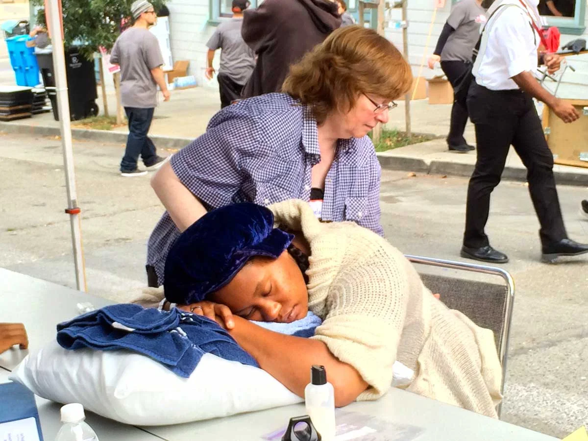 Volunteer massage therapist offering chair massage at a community partner site.
