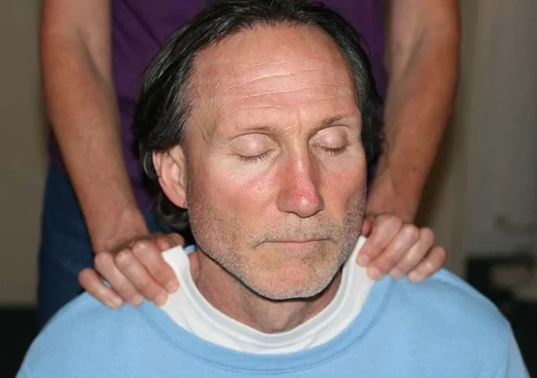 Volunteer massage therapist offering free chair massage to someone facing barriers to care.