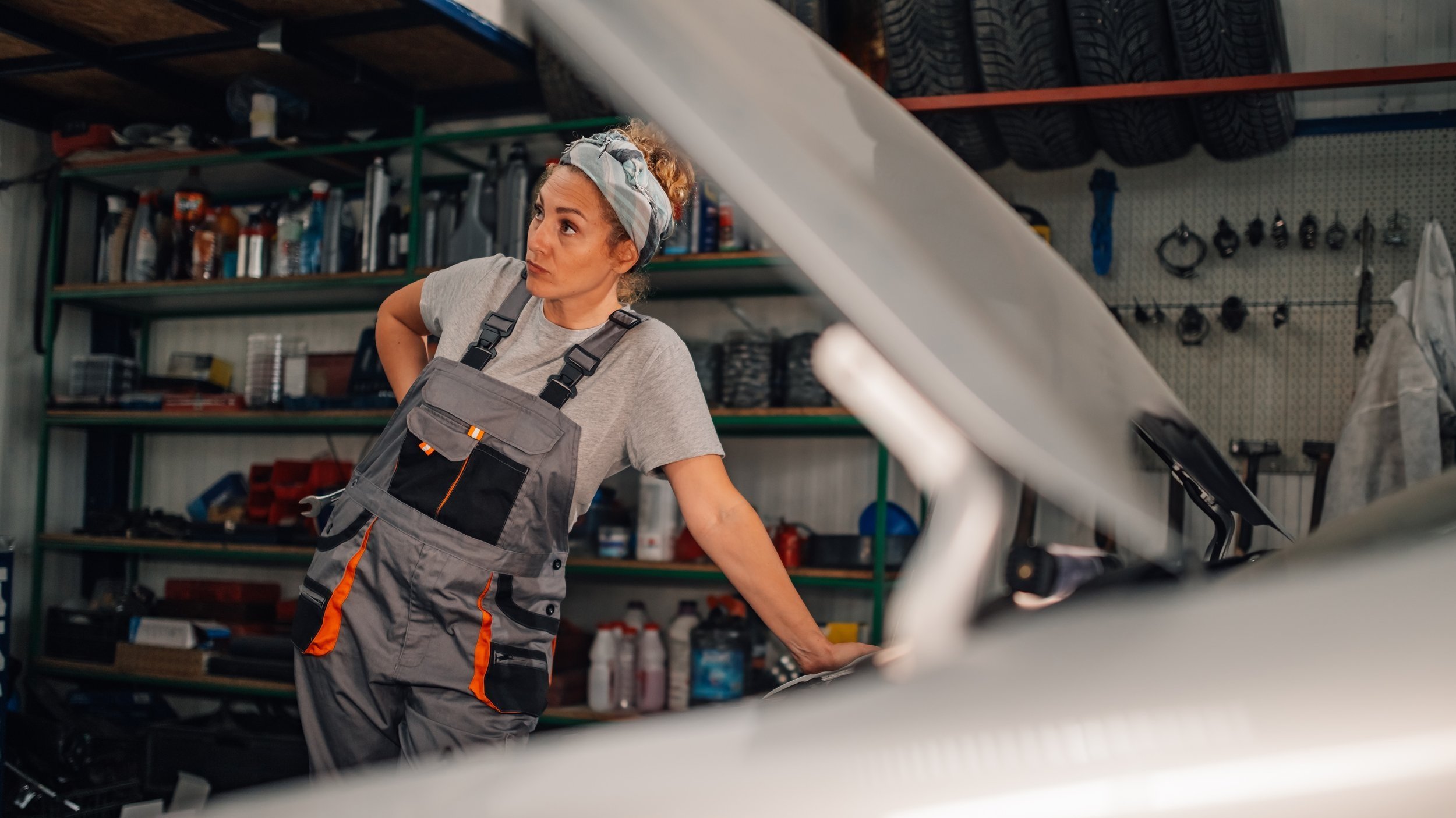 female-mechanic-leaning-on-broken-car-and-looking-2024-07-12-17-41-22-utc.jpg